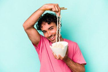 Mavi arka planda izole edilmiş erişte yiyen genç beyaz bir adam.