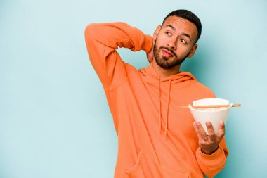 Mavi arka planda izole edilmiş erişte yiyen genç İspanyol kadın kafasının arkasına dokunuyor, düşünüyor ve bir seçim yapıyor..