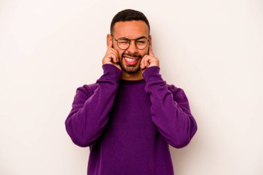 Beyaz arka planda izole edilmiş genç İspanyol adam kulaklarını elleriyle kapatıyor..