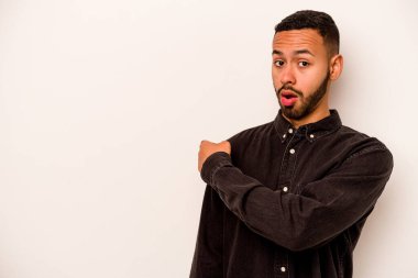 Beyaz arka planda izole edilmiş genç İspanyol adam gülümsüyor ve boş alanda bir şeyler gösteriyor..