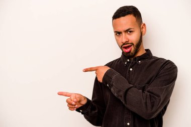 Beyaz arka planda izole edilmiş genç İspanyol adam işaret parmaklarıyla fotokopi alanını işaret ederek heyecan ve arzuyu ifade ediyor..