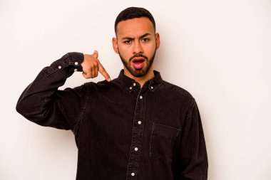Beyaz arka planda izole edilmiş genç bir İspanyol gömlek fotokopi alanını elle işaret ediyor, gururlu ve kendinden emin.