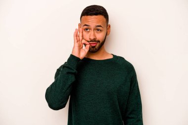 Beyaz arka planda izole edilmiş genç İspanyol adam parmakları dudaklarında bir sır saklıyor..