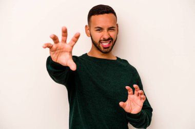 Beyaz arka planda izole edilmiş genç İspanyol bir adam pençelerini bir kediyi taklit ederken gösteriyor, agresif bir hareket..