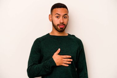 Beyaz arka planda izole edilmiş genç İspanyol adam karnına dokunuyor, nazikçe gülümsüyor, yemek yiyor ve tatmin oluyor..