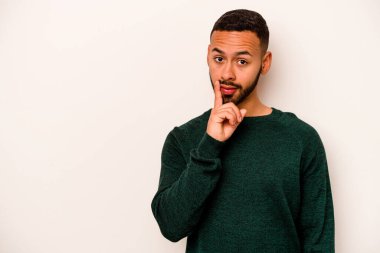 Beyaz arka planda izole edilmiş genç bir İspanyol şüpheli ve şüpheci bir ifadeyle yana bakıyor..