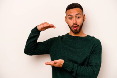 Beyaz arka planda izole edilmiş genç İspanyol adam elleri arasında bir kopya alanı tutarken şok ve hayrete düştü..