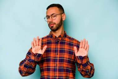 Genç İspanyol bir adam mavi arka planda izole edilmiş, tiksinti gösteren birini reddediyor..