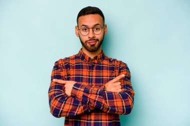 Mavi arka plan noktalarında izole edilmiş genç İspanyol adam iki seçenek arasında seçim yapmaya çalışıyor..