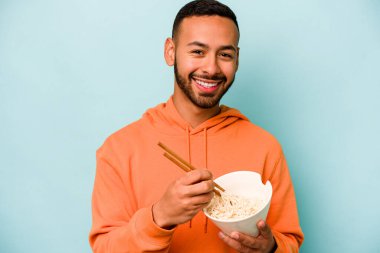 Mavi arka planda izole edilmiş erişte yiyen genç İspanyol kadın.