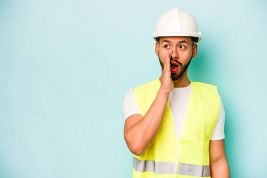 Genç ispanyol işçi mavi arka planda izole edilmiş gizli bir sıcak fren haberi söylüyor ve yana bakıyor