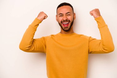 Beyaz arka planda izole edilmiş genç İspanyol bir adam zaferden sonra yumruk kaldırıyor, kazanan konsept..