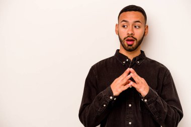 Latin kökenli genç bir adam beyaz arka planda izole edilmiş. Aklında bir plan kuruyor..