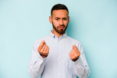 Genç İspanyol adam mavi arka planda izole edilmiş, parasız olduğunu gösteriyor..