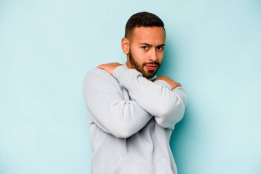 Genç İspanyol adam mavi arka planda yalnızdı. Kucaklaşma, kaygısız gülümseme ve mutluluk..