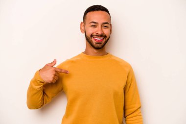 Beyaz arka planda izole edilmiş genç bir İspanyol gömlek fotokopi alanını elle işaret ediyor, gururlu ve kendinden emin.