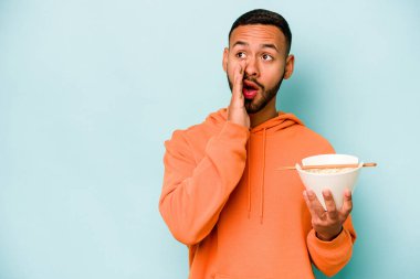 Mavi arka planda izole edilmiş erişte yiyen genç İspanyol kadın gizli bir sıcak fren haberi veriyor ve bir kenara bakıyor.