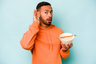 Mavi arka planda izole edilmiş erişte yiyen genç İspanyol kadın bir dedikoduyu dinlemeye çalışıyor..