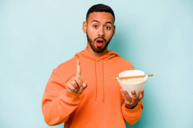 Mavi arka planda izole edilmiş erişte yiyen Latin kökenli genç bir kadın yaratıcılık kavramına sahip..