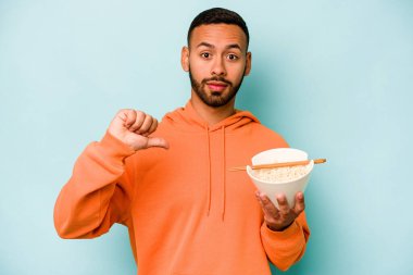 Mavi arka planda izole edilmiş erişte yiyen genç İspanyol kadın hoş olmayan bir jest gösteriyor. Anlaşmazlık konsepti.