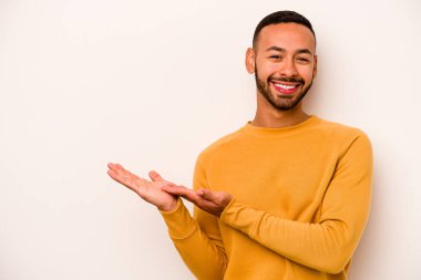 Beyaz arka planda izole edilmiş genç İspanyol bir adam avucunun içinde bir kopyasını tutuyor..