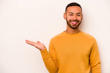 Beyaz arka planda izole edilmiş genç İspanyol bir adam bir avuç içinde fotokopi alanı ve belinde bir el daha gösteriyor..