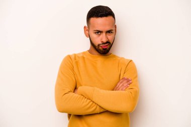 Beyaz arka planda izole edilmiş, hoşnutsuzca kaşlarını çatmış, kollarını kavuşturmuş genç bir İspanyol..