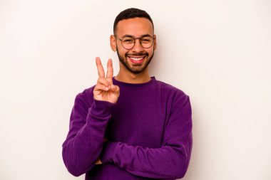 Beyaz arka planda izole edilmiş genç İspanyol adam iki numarayı parmaklarıyla gösteriyor..