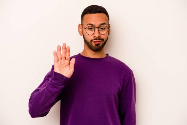 Beyaz arka planda izole edilmiş genç İspanyol adam gülümseyerek beş numarayı parmaklarıyla gösteriyor..
