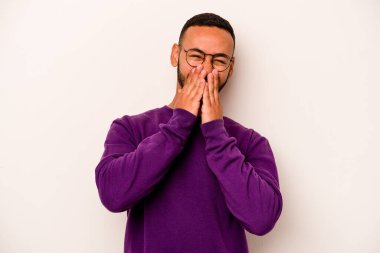 Beyaz arka planda izole edilmiş genç İspanyol bir adam bir şeye gülüyor, elleriyle ağzını kapatıyor..