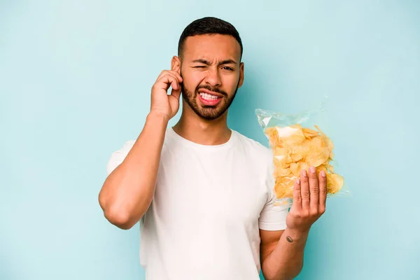 Young Hispanic Man Holding Bag Chips Isolated Blue Background Covering — Stock fotografie