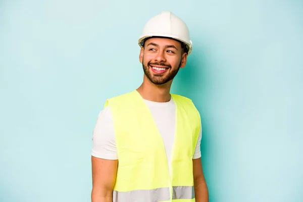 Young Laborer Hispanic Man Isolated Blue Background Looks Aside Smiling — 스톡 사진