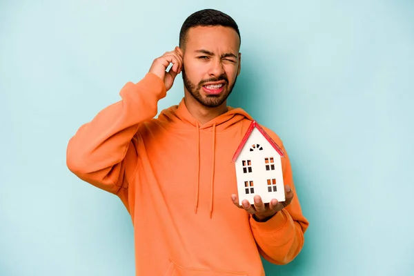 Young Hispanic Man Holding Toy House Isolated Blue Background Covering — Stock Photo, Image