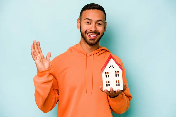 Young Hispanic Man Holding Toy House Isolated Blue Background Receiving — Stok fotoğraf
