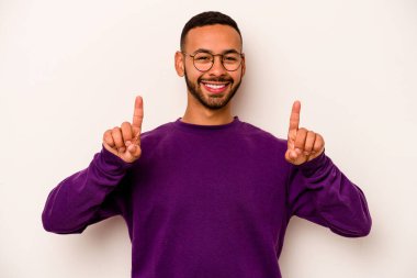 Beyaz arka planda izole edilmiş genç İspanyol bir adam iki parmağı da boş bir alan gösteriyor..