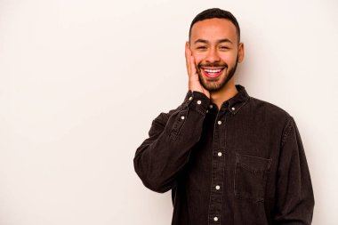 Beyaz arka planda izole edilmiş genç bir İspanyol yüksek sesle bağırıyor, gözleri açık ve elleri gergin tutuyor..