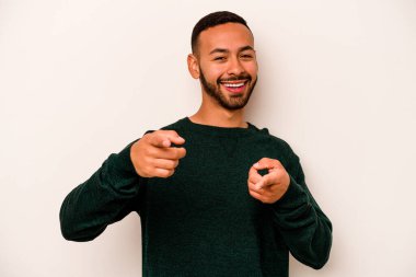 Beyaz arka planda izole edilmiş genç İspanyol adam parmaklarıyla ön tarafı işaret ediyor..