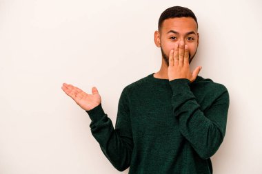 Beyaz arka planda izole edilmiş genç İspanyol adam, avuç içinde kopya alanı tutmaktan etkilenmiş..