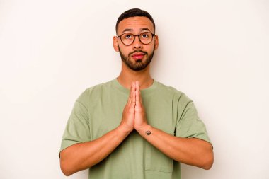 Beyaz arka planda izole edilmiş genç bir İspanyol. El ele tutuşup dua ediyor. Kendine güveniyor..