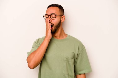 Beyaz arka planda izole edilmiş genç İspanyol adam esniyor. Ağzı eliyle kapatan yorgun bir hareket sergiliyor..