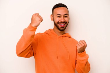 Beyaz arka planda izole edilmiş genç bir İspanyol tasasız ve heyecanlı bir şekilde tezahürat yapıyor. Zafer konsepti.