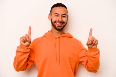 Beyaz arka planda izole edilmiş genç İspanyol bir adam iki parmağı da boş bir alan gösteriyor..