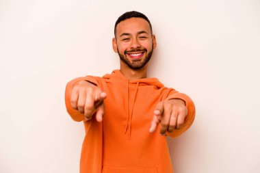 Beyaz arka planda izole edilmiş genç İspanyol adam parmaklarıyla ön tarafı işaret ediyor..