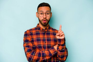 Latin kökenli genç bir adam mavi arka planda izole edilmiş. Harika bir fikri var, yaratıcılık kavramı..