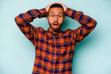 Genç İspanyol adam mavi arka planda izole edilmiş bağırıyor, çok heyecanlı, tutkulu, bir şeyden memnun..