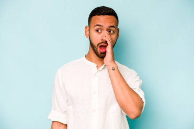 Genç İspanyol adam mavi arka planda izole edilmiş, heyecanlı bir şekilde bağırıyor..