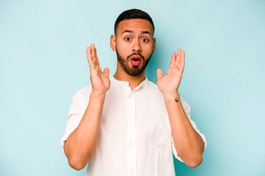 Genç İspanyol adam mavi arka planda izole edildi. Şaşırdı ve şok oldu..