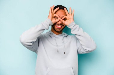 Latin kökenli genç adam mavi arka planda izole edilmiş. Heyecanlı..