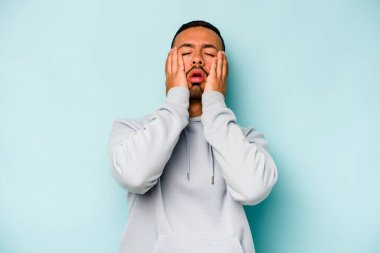 Genç İspanyol adam mavi arka planda yalnızdı sızlanıyor ve ağlıyordu..
