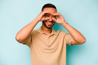 Mavi arka planda izole edilmiş genç İspanyol adam gözlerinde iyi işaretler gösteriyor.